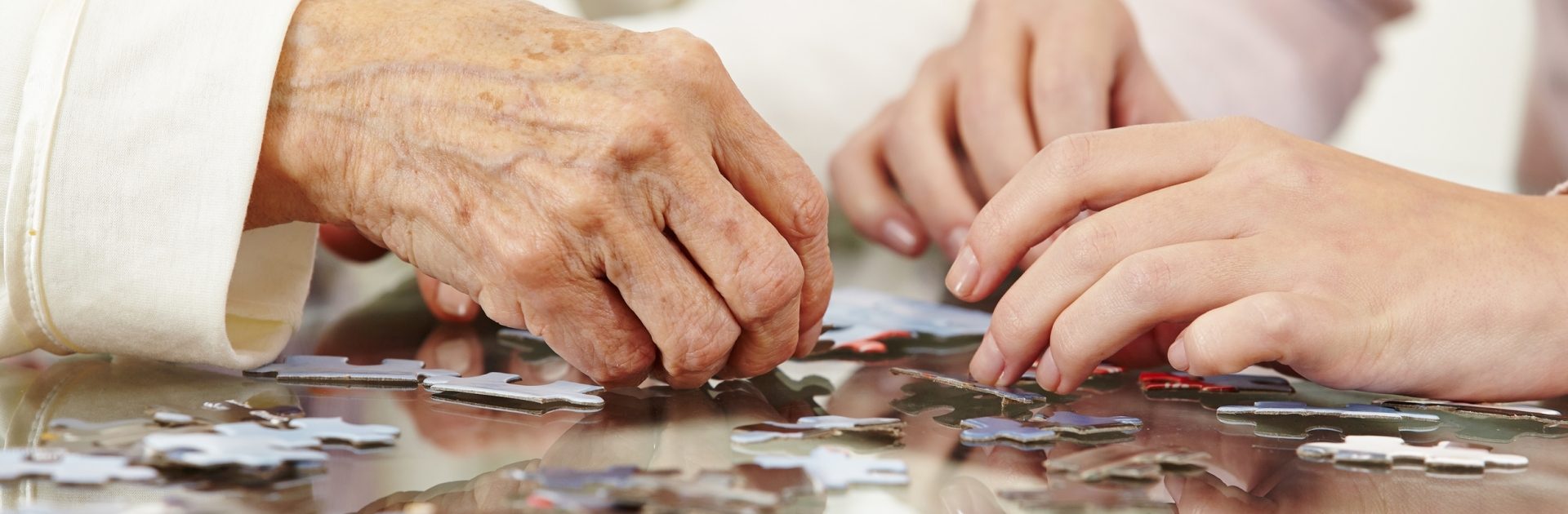 Old hands solving jigsaw puzzle in a nursing home